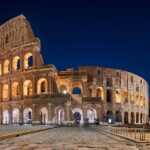 A night view of the Colosseum in Rome, Italy, illuminated against the dark sky.